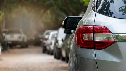 Rear view of a car in a residential parking lot. Visible taillights of a gray car and blurred of...