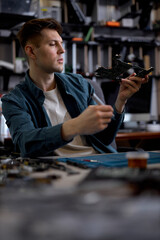 Confident caucasian repairman or engineer restores the laptop PC examining the details of parts of disassembled laptop. Electronic repair shop, technology renovation, business, concept repairs.