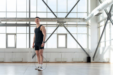 Smiling hispanic man working out in gym using jump rope. ?oncept of health care training in gym