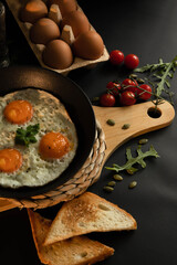 Fried glaze eggs in a frying pan on a black background