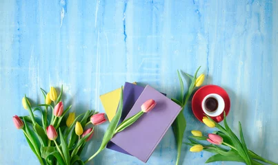 Fototapeten beautiful spring flowers, row of colorful tulips flowers with books and cup of coffee on blue background, concept, flat lay, negative space,free copy space © Kirsten Hinte