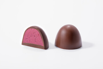 Round chocolates with colored raspberry filling on a white background