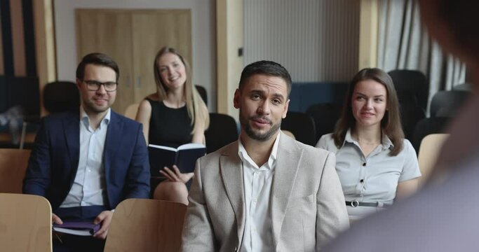 Company intern man asking question to presenter, mentor on business conference, training, raising hand, speaking, listening to answer. Audience of participants sitting in rows, looking at speaker