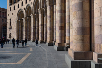 Tourist crowd walking along stone colonnade of building on Republic Square, Yerevan, Armenia