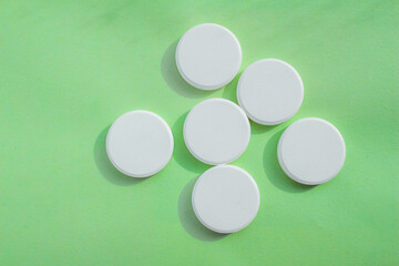 White soluble tablet pills isolated on a green background. Top view, flat lay. Copy space for text. - obrazy, fototapety, plakaty