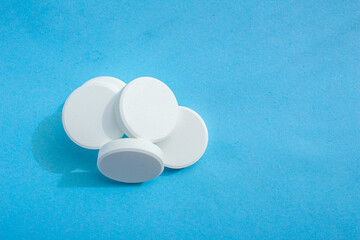 White soluble tablet pills isolated on a blue background. Top view, flat lay. Copy space for text.