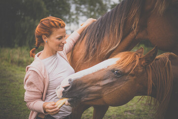 Pretty, young, redhead woman with her lovely horse, during her favorite leisure