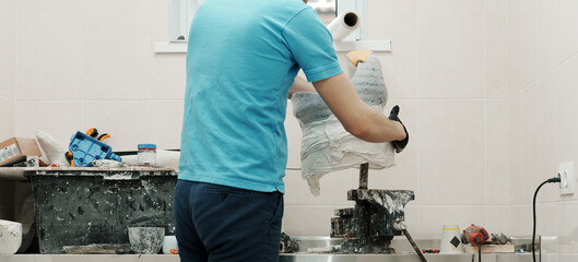 Closeup of crop unrecognizable male worker in black rubber gloves making hip disarticulation prosthesis mold with wet plaster in professional workshop