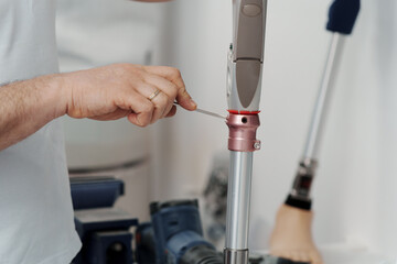 Crop anonymous manual worker fixing mechanism of new artificial limb with screwdriver while assembling leg prosthesis in workshop