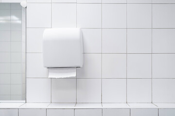 Folded hand towel dispensers close up with white colour ceramic tiles toilet . White colour theme...