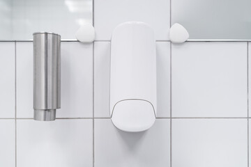 Hand soap dispensers close up with white colour ceramic tiles toilet . White colour theme toilet interior. Cleanliness concept. Clean toilet concept.