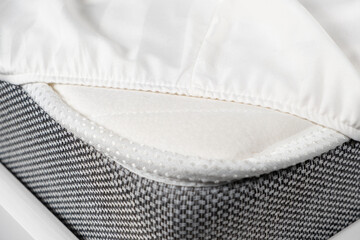 White satin sheet on an elastic band on the mattress. Bed linen on the bed