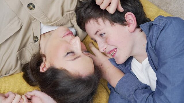 Top view Happy mother and son laughing playing having fun lying on floor at home. Positive emotion and joyful family concept. cheerful mom and kid boy playful are laughing hug together from above