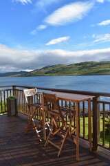 wooden brown bench and table stand outdoor at bacolny  over the sea of skye island  ,blue and white sky