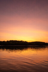 Obraz premium Sunrise view with colorful sky and the sea, with silhouette of the forest on the background