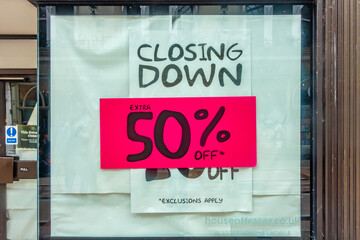 A poster in a shop window advertising 50% discounts as the store is closing down.