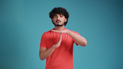 indian man with beard wearing coral t-shirt isolated on a blue studio background doing time out...