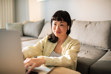 Fototapeta premium Young Japanese Woman using a laptop on a couch