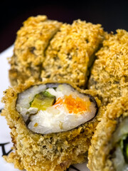 sushi and rolls on the white Japanese plate on black background