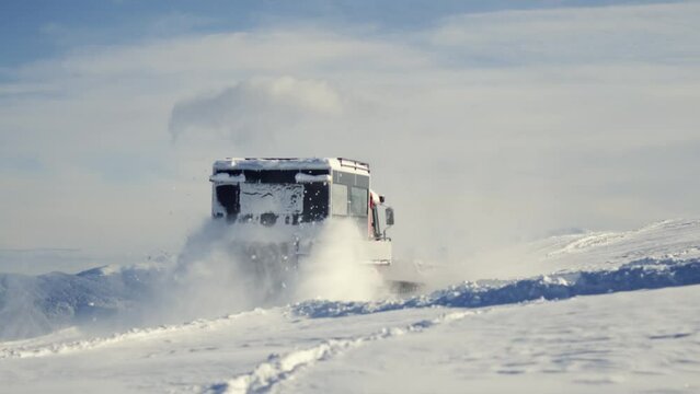Modern snowcat ratrack with snowplow,snow grooming machine,remover truck preparing ski slope,piste,hill at alpine skiing winter resort.