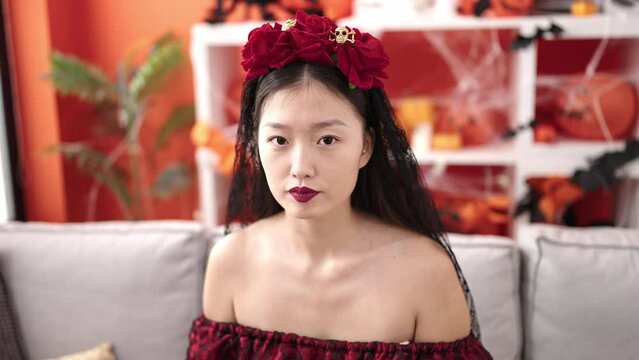 Young chinese woman wearing katrina costume holding skull mask at home