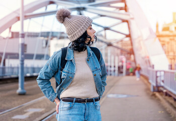 Fototapeta premium a young woman in a denim jacket is talking on the phone and waiting for a tram at the stop Lifestyle photo