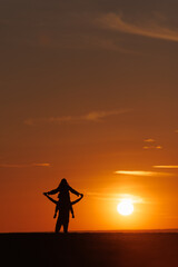 silhouettes of couple at sunset against bright sun sky. man and woman have fun in nature, walking and relaxing, relationships and falling in love. poster postcard romantic meetings against background 