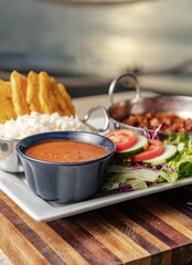 Vertical closeup shot of a gourmet dish with salsa, salad and beans