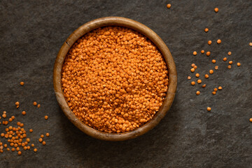 red lentils in a wooden bowl on a black background. Healthy lifestyle. Vegetarian and vegan diet, source of protein