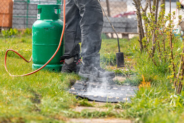 heating asphalt belts for waterproofing the foundation of the house with the help of a gas tank and an open fire