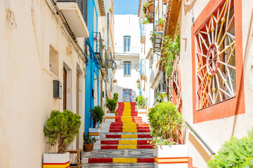 View of Calpe old town on sunny day. Stairs adorned with colors of Spanish flag, Calpe, Alicante province, Valencian Community, Spain