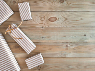 Gift wrapping in retro style. Flat lay with place for text. Eco packaging concept. Boxes wrapped in brown striped paper on wooden background. Top view. Copyspace. Empty space for inscription on right