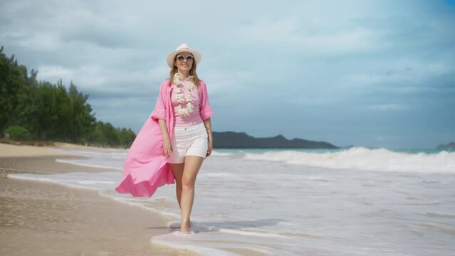 Beautiful elegant American woman wearing traditional Hawaiian lei on sunny Oahu summer beach, Hawaii island USA. Slow motion shot on RED camera 4K. Smiling woman having fun laughing on Hawaii holiday