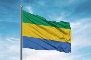 Gabon national flag cloth fabric waving on beautiful sky Background.