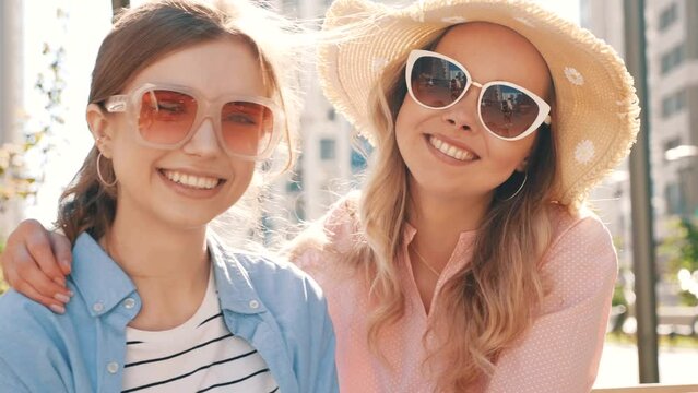Two young beautiful smiling hipster female in trendy summer clothes and dress. carefree women posing in the street. Positive pure models having fun. In sunglasses