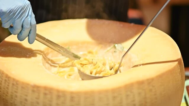 Chef cook preparing italian pasta in a parmesan wheel cheese, burning fire
