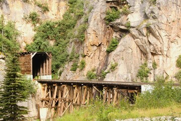 Train tracks running through a mountain range surrounded by trees and green vegetation - 593065775