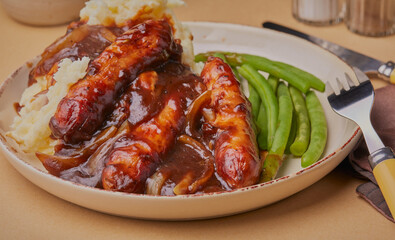 Sausage and mashed potatoes with a rich onion gravy and side portion of runner beans.
