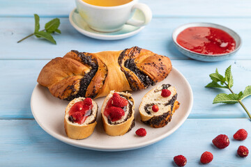 Sweet bun with strawberry jam on a blue wooden background, side view, close up.