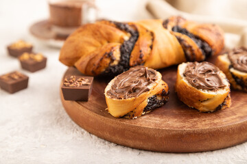 Homemade sweet bun with chocolate cream and cup of coffee on a gray. side view, selective focus.