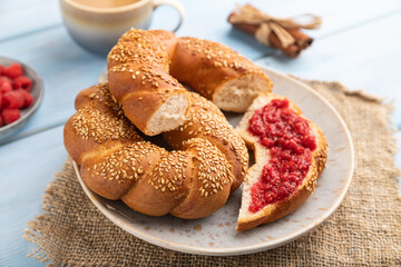 Homemade sweet bun with raspberry jam and cup of coffee on a blue wooden. side view, selective focus.