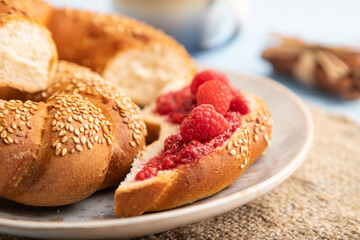 Homemade sweet bun with raspberry jam and cup of coffee on a blue wooden. side view, selective focus.