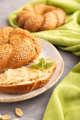 Homemade sweet bun with peanut butter and cup of coffee on a gray concrete. side view, selective focus.