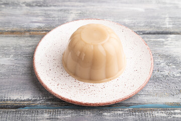 Buckwheat milk jelly on gray wooden, side view, close up.