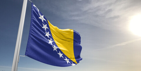 Bosnia and Herzegovina national flag cloth fabric waving on beautiful sky grey Background.