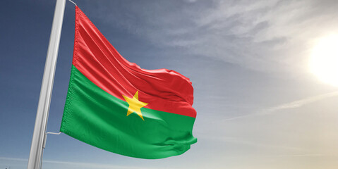 Burkina Faso national flag cloth fabric waving on beautiful sky grey Background.