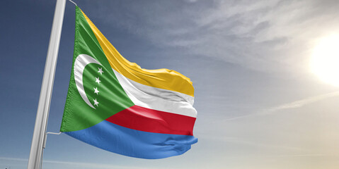 Comoros national flag cloth fabric waving on beautiful sky grey Background.