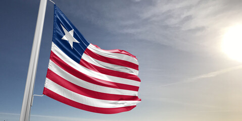 Liberia national flag cloth fabric waving on beautiful sky grey Background.
