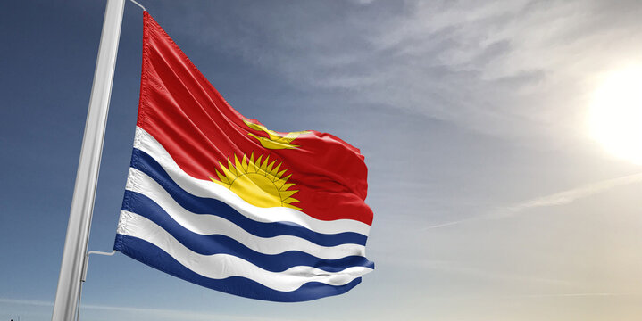 Kiribati national flag cloth fabric waving on beautiful sky grey Background.