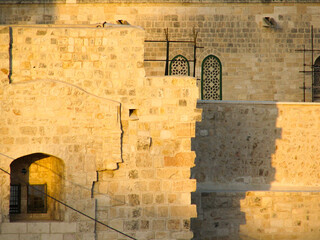 A beautiful ancient stone building in Jerusalem, Israel, with a window and arched decorative pieces, bathed in golden afternoon sunlight.  Image has copy space.